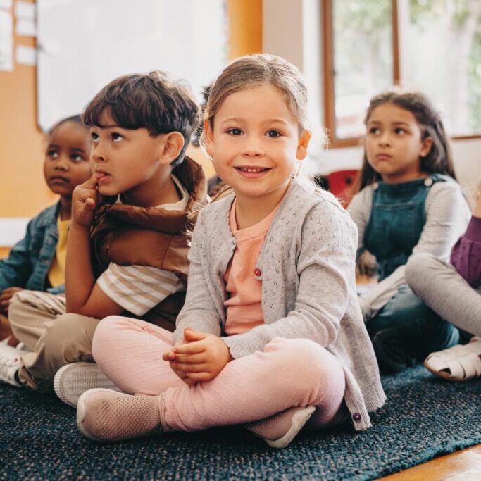 Adorable,Little,Child,Looking,At,The,Camera,While,Sitting,In kindergarten children